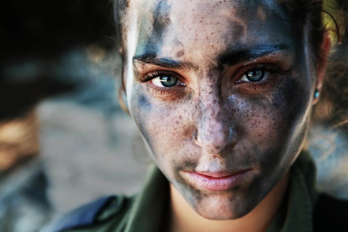 An 18 year old IDF soldier pauses after a long run in full gear and battle paint. Human Diversity